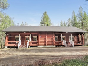 A two-story log cabin with a porch, two doors, and a chimney.