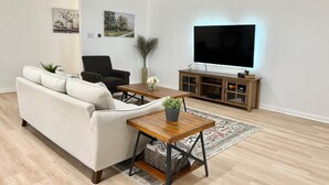 Una sala de estar con un sofá, una mesa de centro, un televisor y un ventilador de techo.