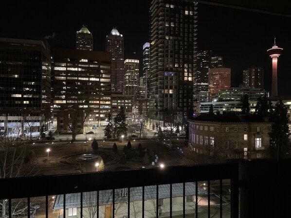 Une vue nocturne d’une ville, avec des bâtiments illuminés et une tour imposante.
