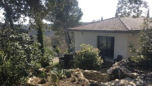 Ein Haus mit einem Ziegeldach, umgeben von einem Garten mit Kakteen und Steinen.