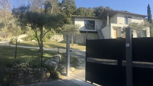 Ein modernes Haus mit Steinverkleidung, einer sichtbaren Treppe und einem umzäunten Garten.