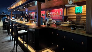 Un espace bar avec un comptoir, des tabourets et un barista qui prépare des boissons.