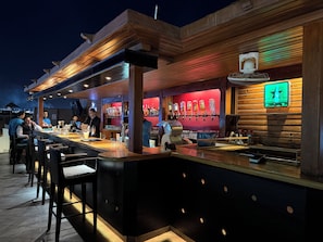 A bar area with a counter, stools, and a barista preparing drinks. - Egyptian Experience Resort in Nabq, studio with sea views (Sharm El Sheikh)