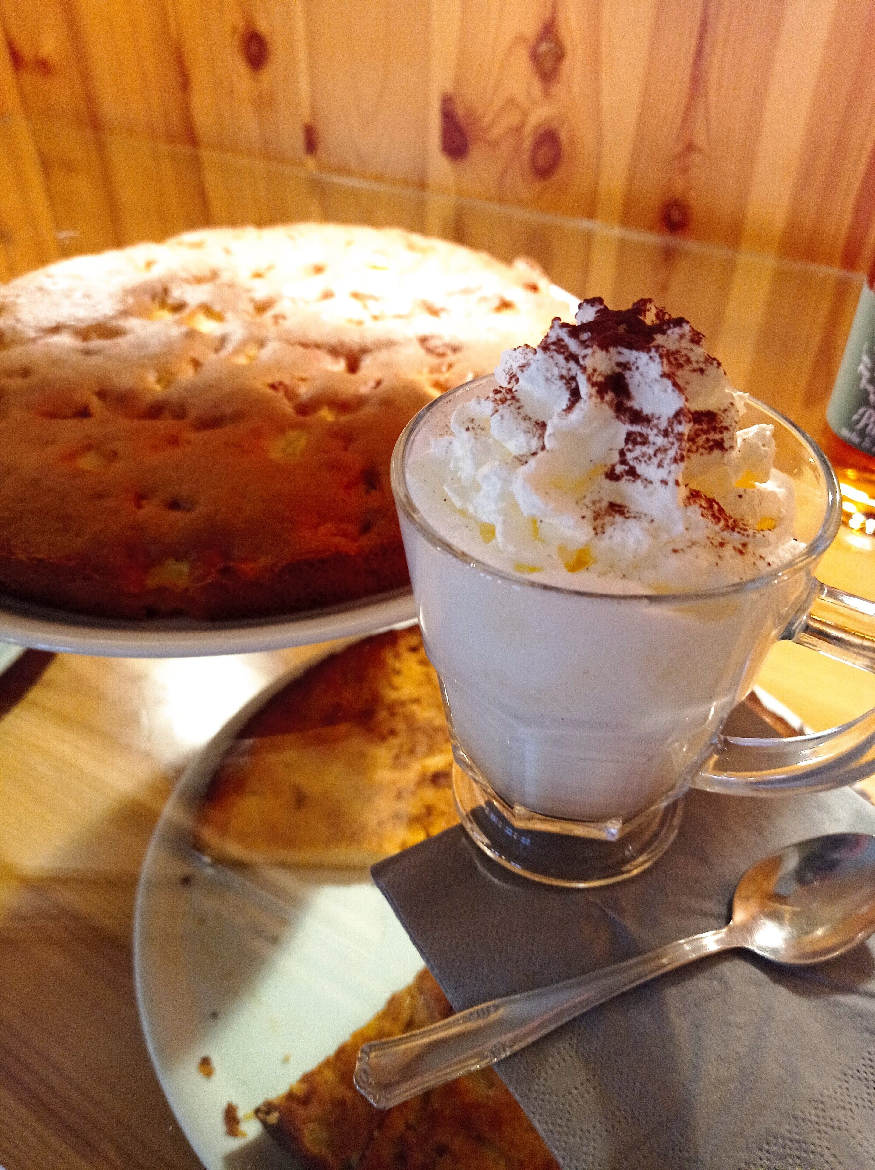 Un dolce composto da una torta e un bicchiere di panna montata con una spolverata di cacao.