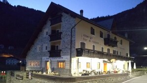 A stone building with a restaurant named "Albergo Fior di Roccia L." It has a balcony and outdoor seating. - Hotel Fior di Roccia Valmalenco (Lanzada)