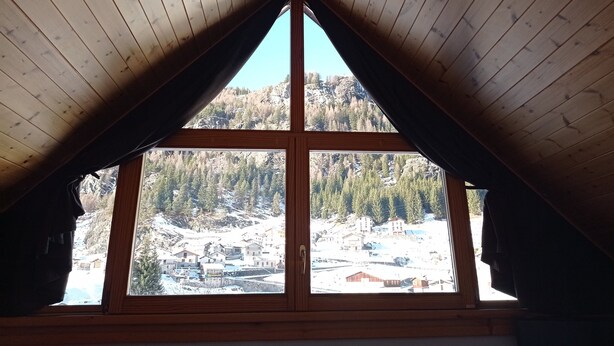 A room with a wooden ceiling and a large window. - Hotel Fior di Roccia Valmalenco (Lanzada)