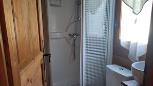 A compact bathroom with a shower, toilet, and sink. - Caravan (Arles)