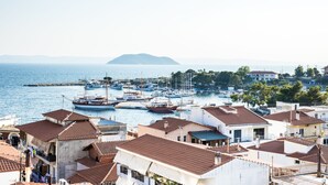 Un pueblo costero con barcos amarrados en un puerto deportivo, rodeado de edificios con tejados de tejas rojas.