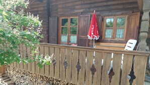 Eine Holzhütte mit einem Holzzaun, einem Holzscheitestapel und einem roten Regenschirm.
