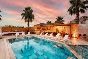 A pool area with lounge chairs, a bar, and a restaurant with outdoor seating. - Le Marden Hotel Spa (Kemer)