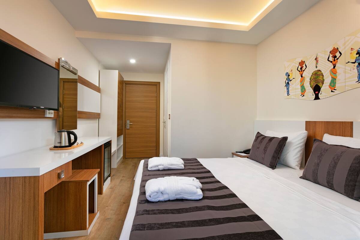 Ein Hotelzimmer mit einem Bett, einem Flachbildfernseher, einem Holztisch und einem Bild an der Wand.