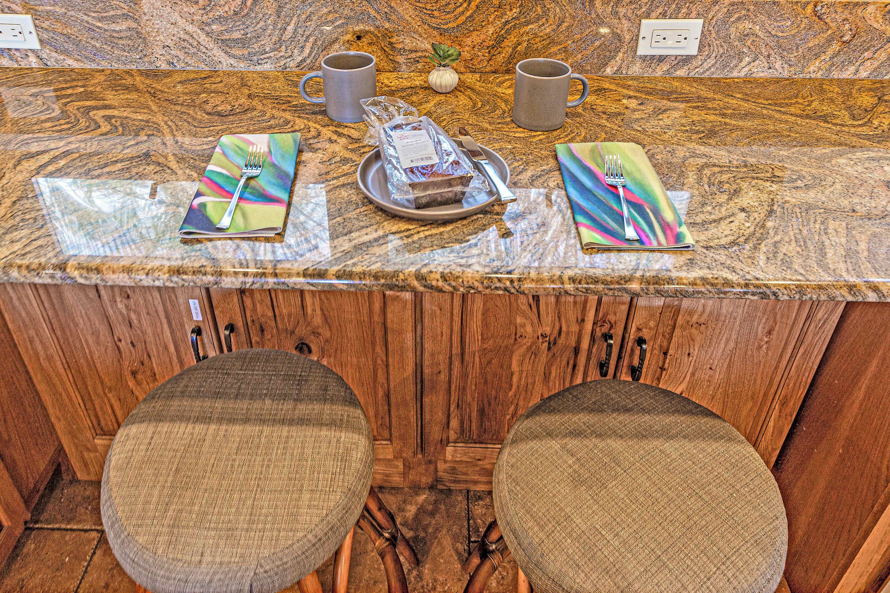 A kitchen counter with a marble top, two chairs with cushioned seats, and a small potted plant.