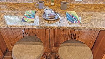 A kitchen counter with a marble top, two chairs with cushioned seats, and a small potted plant.