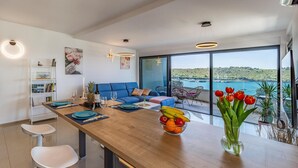 A modern kitchen with a wooden island, a dining area with blue chairs, a sofa, and a view of the sea. - 2 bedroom beautiful apartment in Banjole (Banjole)