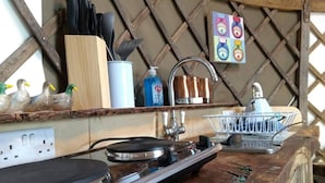 A kitchen counter with a coffee machine, a kettle, and a sink. There are decorative ducks on the counter, a set of knives, and a box of condiments. - Bembridge Harbour Yurt - Log Burner - Wifi (Ryde)