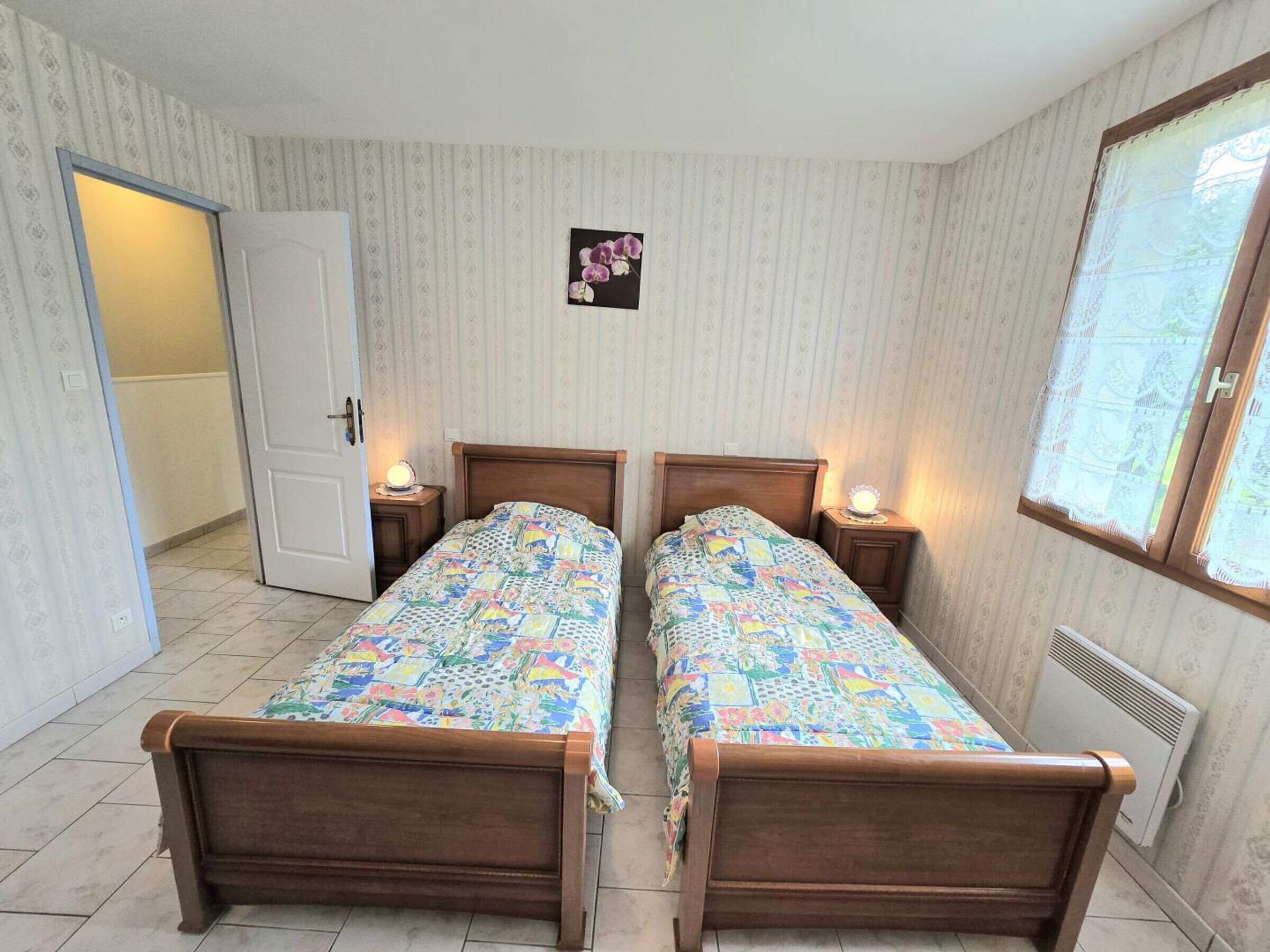 Un dormitorio con dos camas de madera, una puerta, un radiador y una ventana.