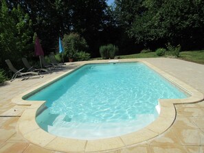 Ein rechteckiger Pool mit Fliesen und Liegestühlen.