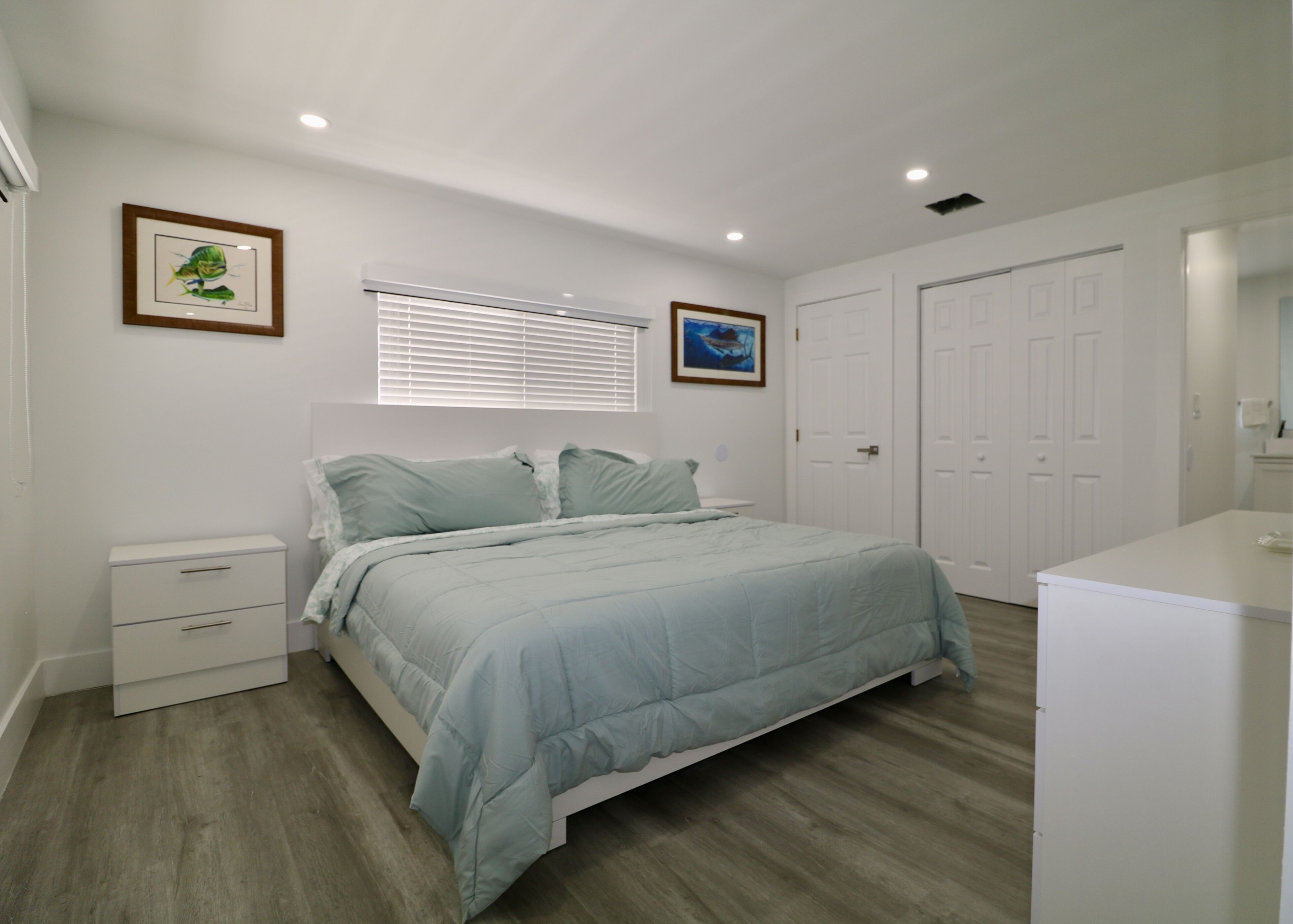 A bedroom with a bed, a nightstand, a dresser, and two doors.