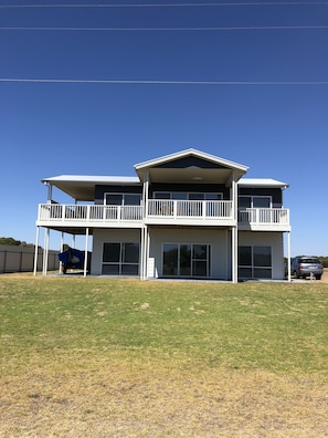 A two-story building with a balcony on the upper floor, large windows, and a covered parking area. - 4 Bedroom Beach House with Sea Views. Now with wifi and foxtel. (Kingston)