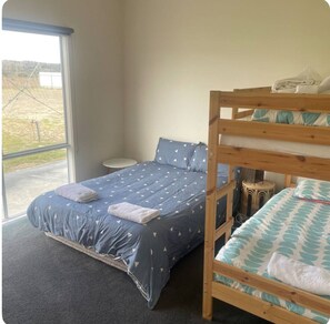 A room with a bunk bed, a single bed, a small round table, and a large window. - 4 Bedroom Beach House with Sea Views. Now with wifi and foxtel. (Kingston)