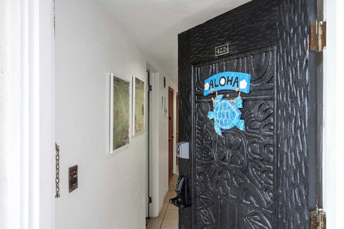 Una porta negra amb un rètol blau que diu "ALOHA" i un emblema decoratiu.