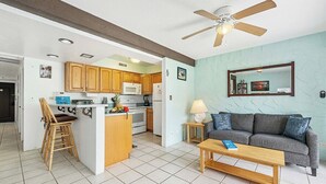 A modern kitchen with wooden cabinets, a central island, and a dining area with a wooden table.