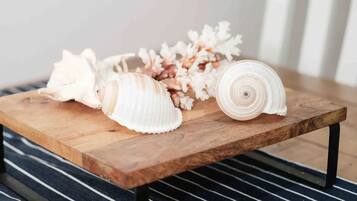 Un tavolo di legno con conchiglie e fiori secchi, su un tappeto a righe.