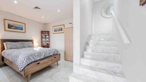 Ein Schlafzimmer mit einem Bett, einem Nachttisch, einem Kleiderschrank und einer Treppe mit Marmorstufen.