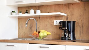 A modern kitchen with a wooden backsplash, a stainless steel sink, a coffee maker, and a fruit bowl. - 2 bedroom lovely apartment in Sibenik (Sibenik)