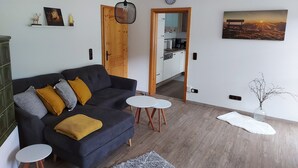 Ein modernes Wohnzimmer mit einem dunkelblauen Sofa, einem kleinen weißen Tisch und Holzboden.