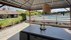 A covered patio area with a pool in the background. - Charming gite for 10 people with heated pool and mini farm near the ocean (Azur)