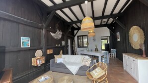 A rustic interior with exposed wooden beams, a dining area with a table and chairs, and a cozy seating area with a sofa and cushions. - Charming gite for 10 people with heated pool and mini farm near the ocean (Azur)