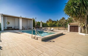 A swimming pool with a sun terrace, lounge chairs, and a covered seating area. - Cozy home in Puente Genil (Puente Genil)