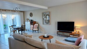 Ein Wohnzimmer mit einer Couch, einem Couchtisch, einem Fernseher und einem Essbereich mit Stühlen und einem Schrank.