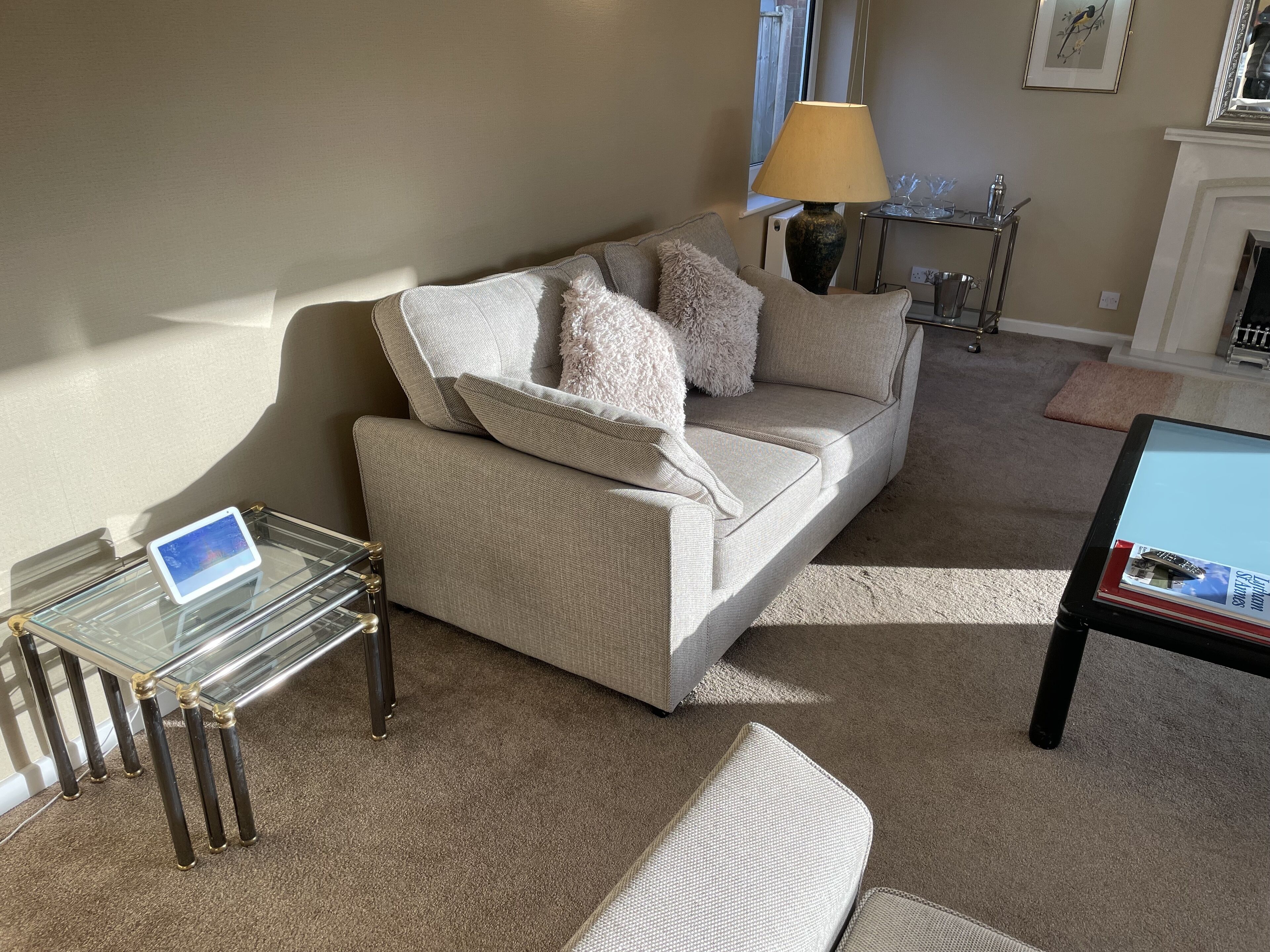 Un salon avec un canapé beige, une table basse en verre, une lampe et une cheminée.