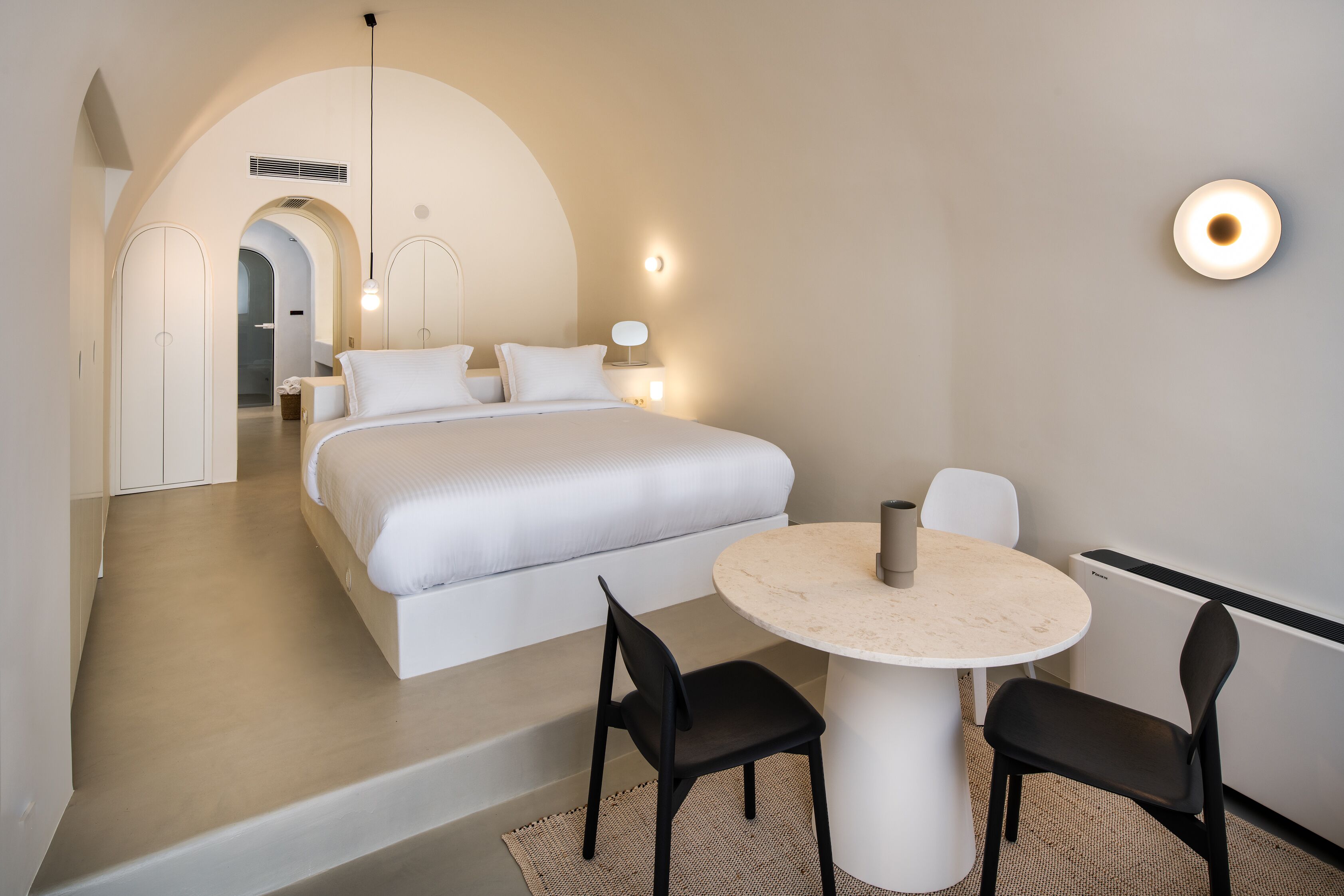 Een moderne hotelkamer met een groot bed, een ronde eettafel en twee stoelen.