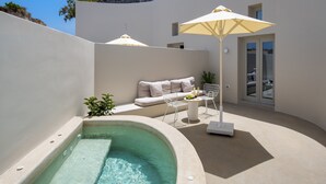 Ein moderner Poolbereich im Freien mit integriertem Whirlpool, einer Lounge mit Sofa und Sesseln sowie einem großen Sonnenschirm, der Schatten spendet.