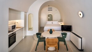 Ein modernes Hotelzimmer mit Küchenzeile, Essbereich und Bett.