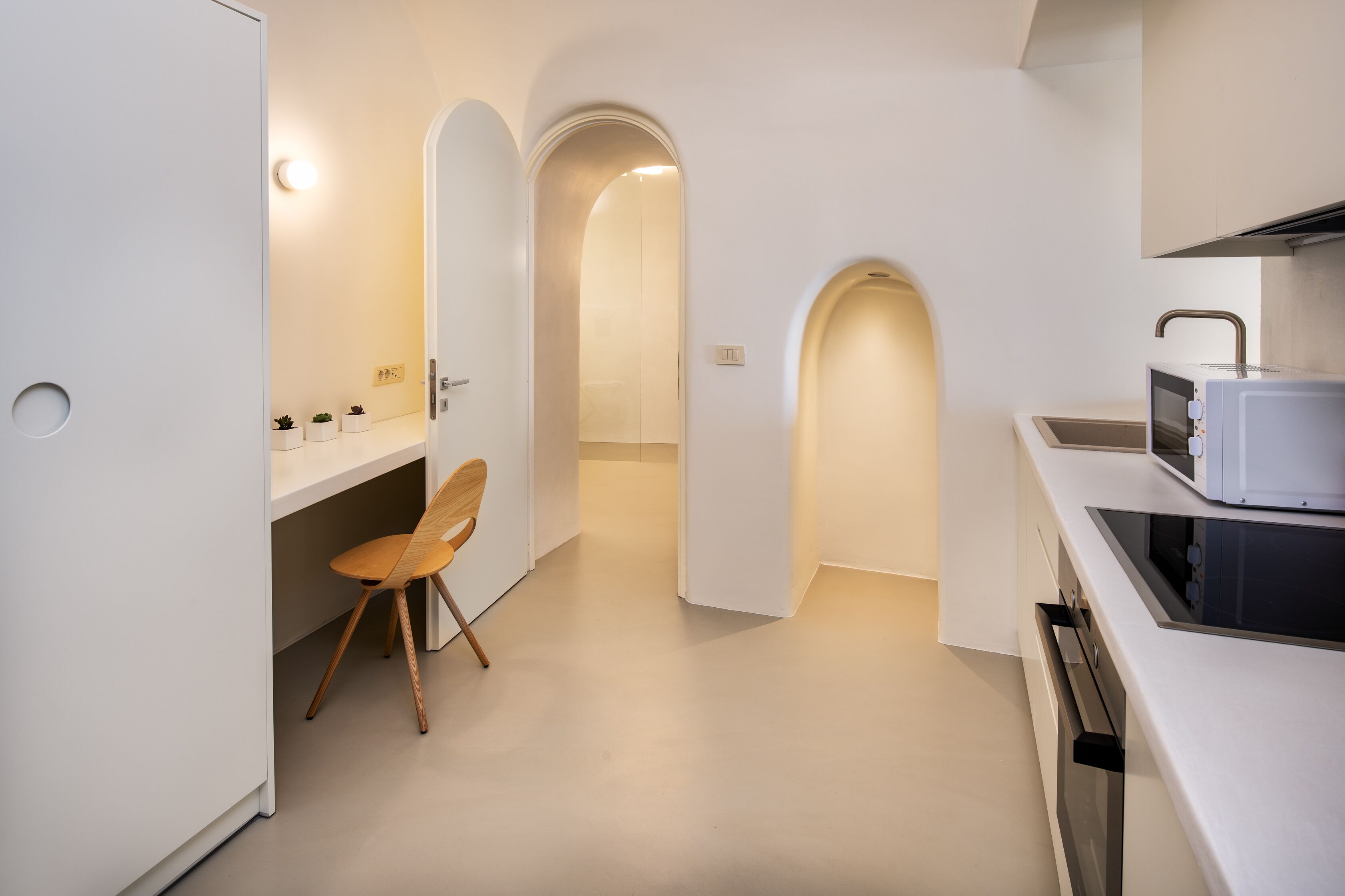 Une cuisine moderne avec des meubles blancs, un four à micro-ondes et un four encastré.