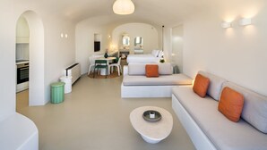 Ein moderner, offener Wohnbereich mit einer Couch, Esstisch und Küchengeräten.