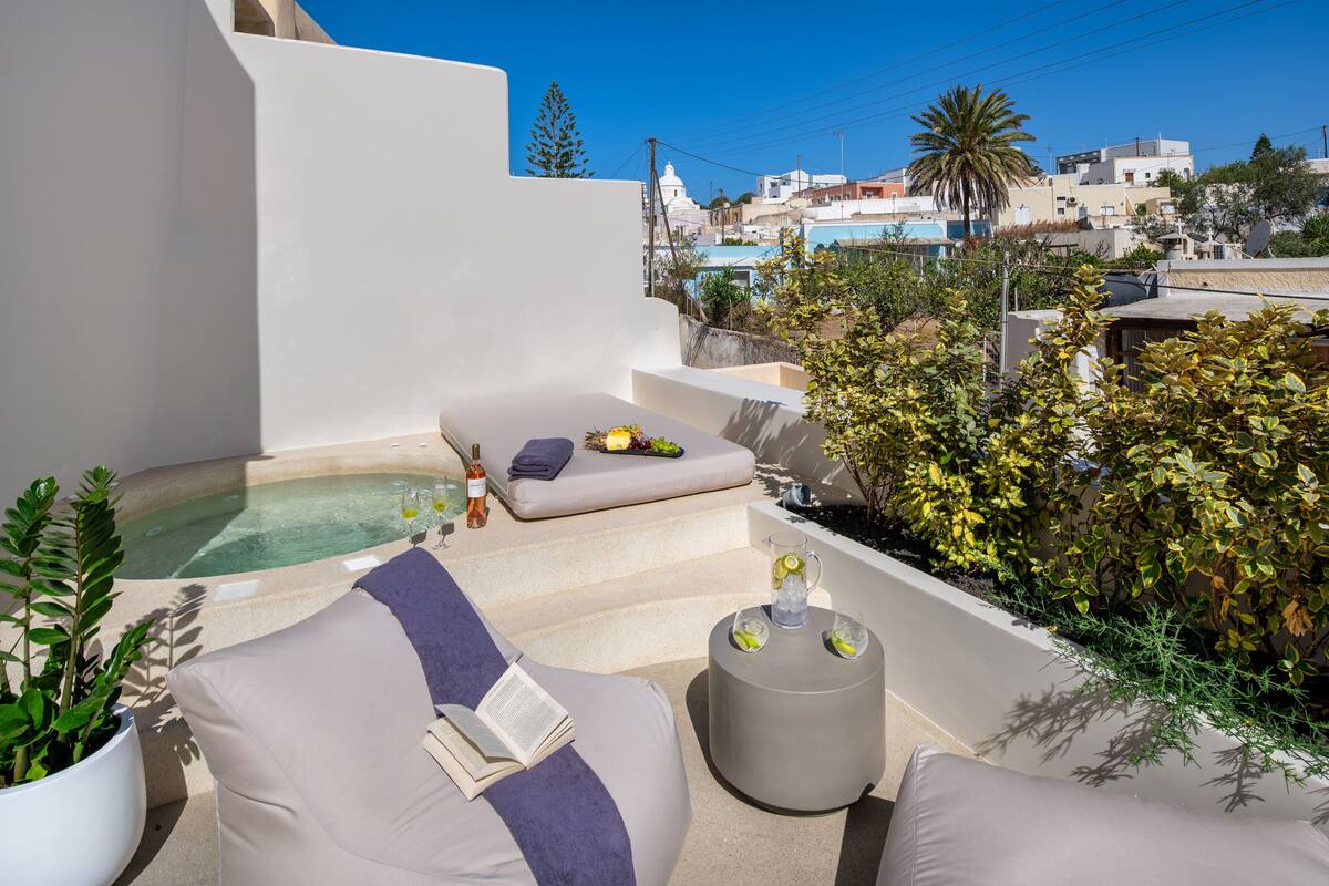Terraza en la azotea con un jacuzzi, sillas de descanso y una mesa pequeña con bebidas.