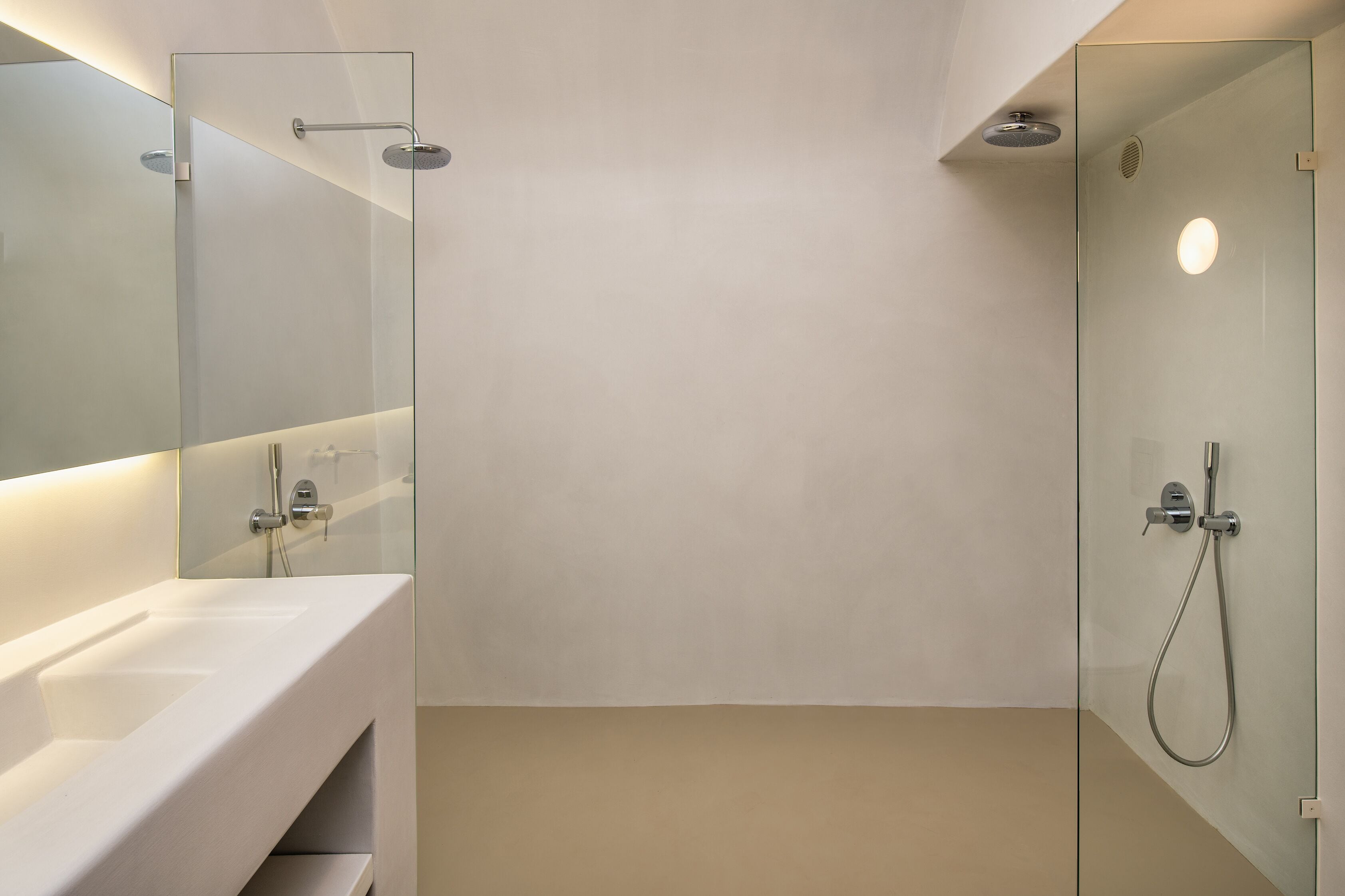 A modern bathroom with a glass shower enclosure, a white sink, and a mirror.