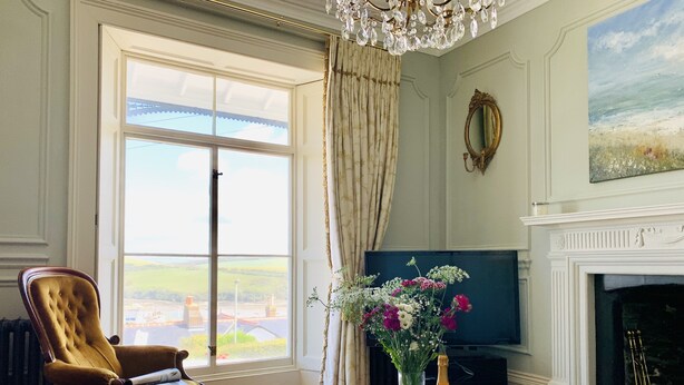 A room with a large window, a television, a fireplace, and a wooden coffee table with a tray and glasses. - Unique period house in the heart of Salcombe (Salcombe)