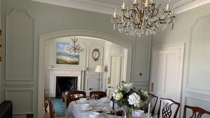 A dining room with a long table set for a meal, a chandelier, and a fireplace in the background. - Unique period house in the heart of Salcombe (Salcombe)