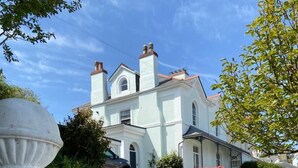 A two-story building with a white facade, a driveway leading to the entrance, and a car parked in front. - Unique period house in the heart of Salcombe (Salcombe)