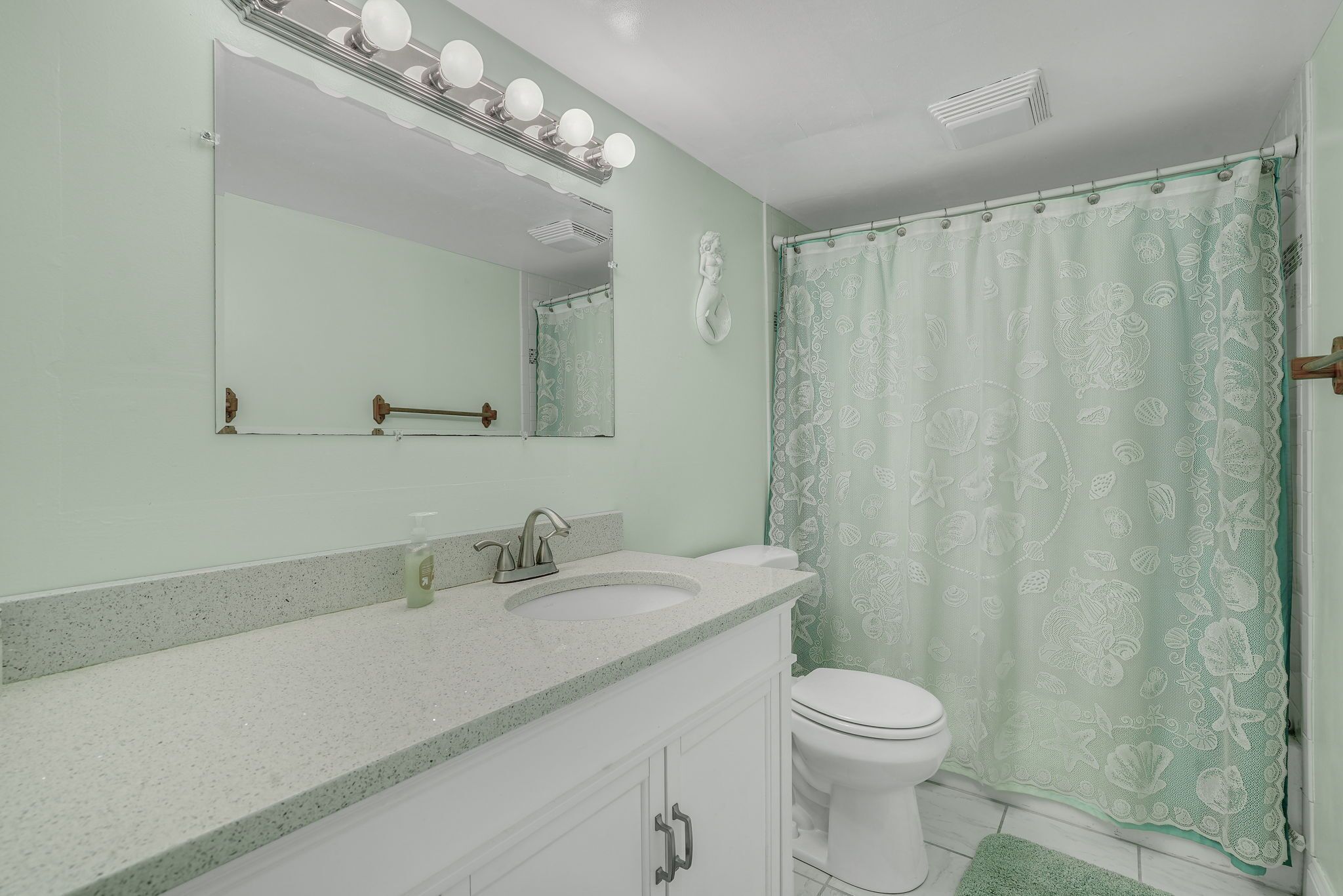 A bathroom with a vanity, sink, mirror, and toilet.