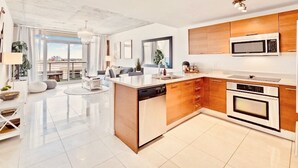 Een moderne keuken met een centraal eiland, ingebouwde apparatuur en een groot raam met uitzicht op de stad.