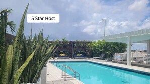 Zwembad van een 5-sterrenhotel met heldere lucht, palmbomen en ligbedden.