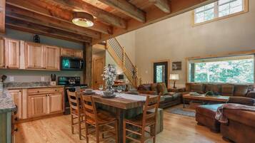 A spacious living area with a wooden dining table, a sofa, and a staircase leading to another level.