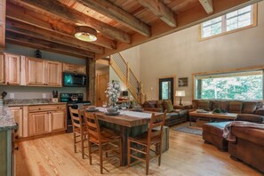 Un'ampia zona giorno con un tavolo da pranzo in legno, un divano e una scala che conduce a un altro livello.